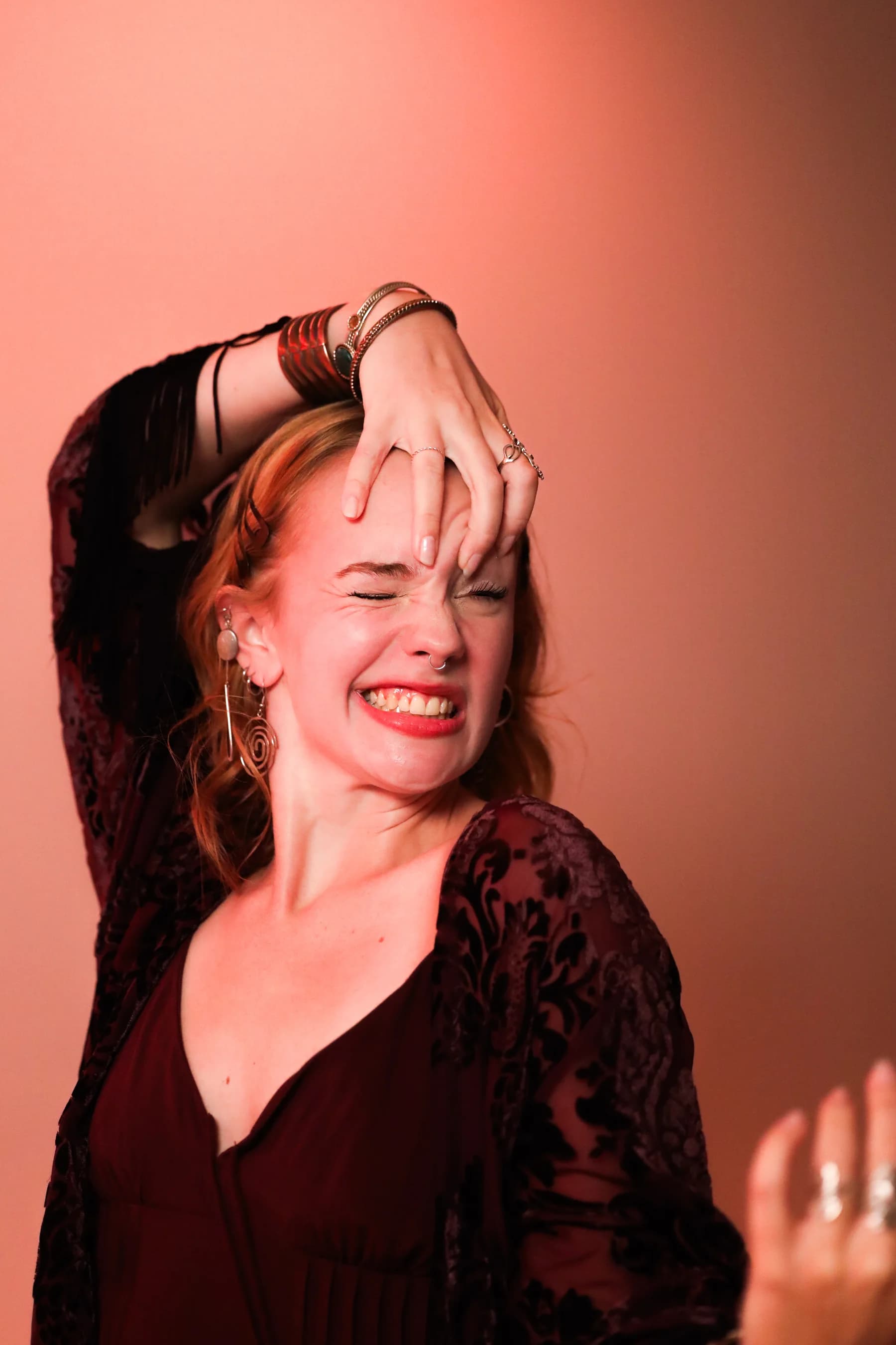 Expressive studio portrait of a dancer smiling with a hand over her forehead