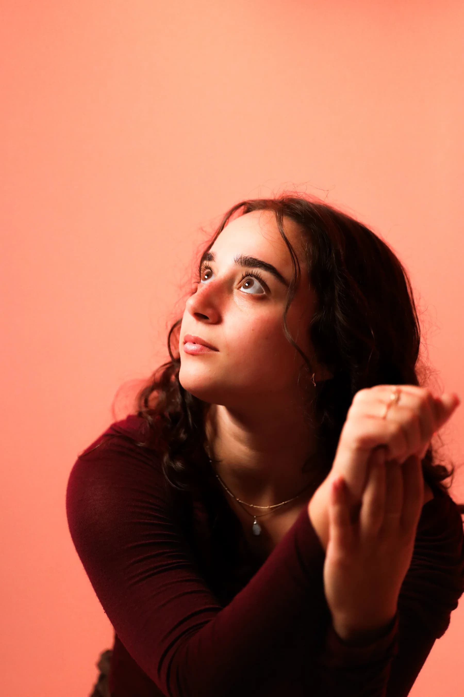 Expressive studio portrait of a dancer looking upward with one hand raised
